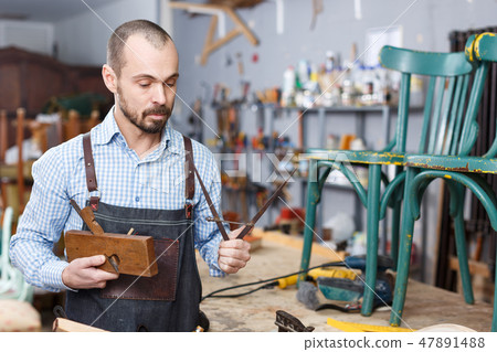 Restorer holding tools in woodwork studio 47891488