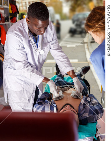 Rescue team making defibrillation to patient 47891765