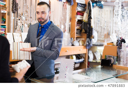 Cheerful male offering to buy fashionable necklace Cheerful male offering to buy fashionable necklace 47891883