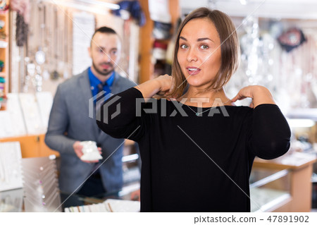 Female consumer trying chainlet with pendants 47891902