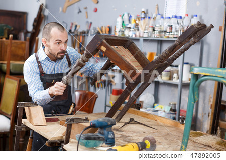 Artisan inspecting old chair Artisan inspecting old chair 47892005
