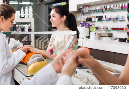 positive female manicurist filing and shaping nails in beauty salon positive female manicurist filing and shaping nails in beauty salon 47892010