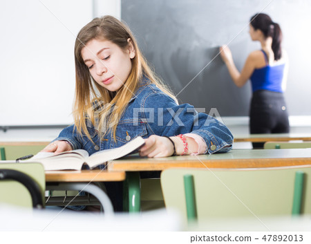 Smiling schoolgirl is learning at the desk Smiling schoolgirl is learning at the desk 47892013
