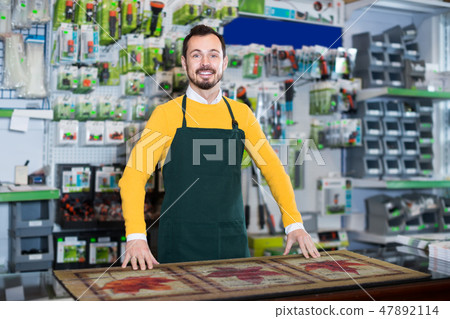 vigorous male seller showing assortment in garden equipment shop 47892114