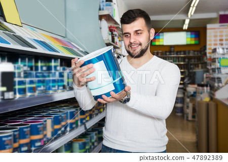 Guy is deciding on best wall paint Guy is deciding on best wall paint 47892389