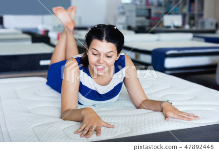 Female is lying on mattress for testing it in the store. Female is lying on mattress for testing it in the store. 47892448