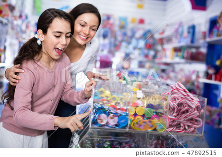 Woman with emotional daughter choosing candies in the candy shop 47892515