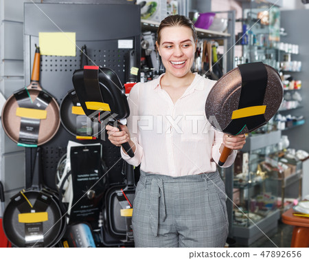 Glad woman is choosing new stewpot for her kitchen 47892656
