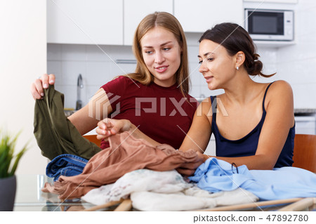 Women showing each other clothes Women showing each other clothes 47892780
