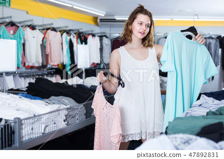 Young female customer selecting new garments Young female customer selecting new garments 47892831