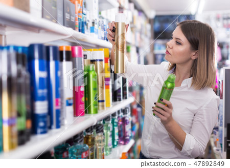 Serious girl looking hair care products at showroom Serious girl looking hair care products at showroom 47892849