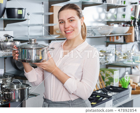 Female customer choosing new pan for kitchen in the kitchenware shop Female customer choosing new pan for kitchen in the kitchenware shop 47892854