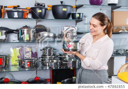 Attractive adult woman is buying new stewpot for kitchen in tableware shop Attractive adult woman is buying new stewpot for kitchen in tableware shop 47892855