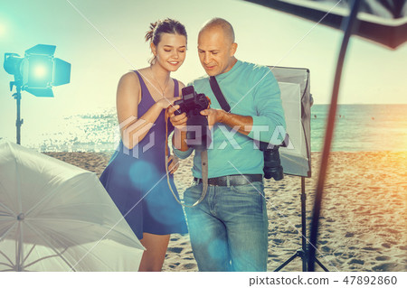 Photographer and model discussing picture on camera display duri Photographer and model discussing picture on camera display duri 47892860