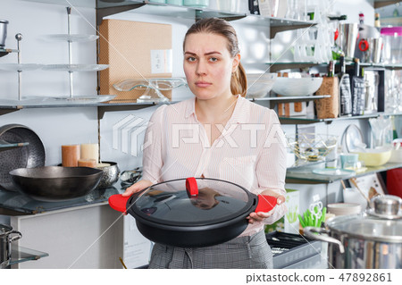 Woman is choosing new stewpot for her kitchen in tableware shop Woman is choosing new stewpot for her kitchen in tableware shop 47892861
