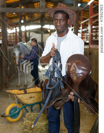 Farm workers preparing horse harness Farm workers preparing horse harness 47892903