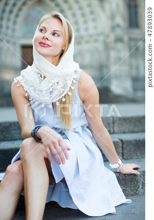 smiling woman sitting in the city center in shawl smiling woman sitting in the city center in shawl 47893039