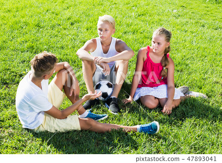 Friends resting after game with ball Friends resting after game with ball 47893041
