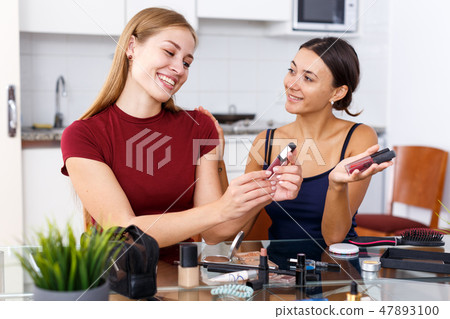 Female friends applying cosmetics Female friends applying cosmetics 47893100