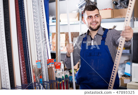 worker choosing plastic edging for tiles and flooring in workshop 47893325