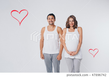 Family portrait: the husband embraces the pregnant wife on a white background. pregnant couple in Family portrait: the husband embraces the pregnant wife on a white background. pregnant couple in 47896742
