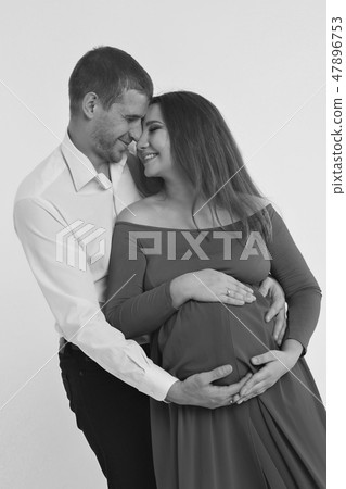 Family portrait: the husband embraces the pregnant wife on a white background. pregnant couple in Family portrait: the husband embraces the pregnant wife on a white background. pregnant couple in 47896753
