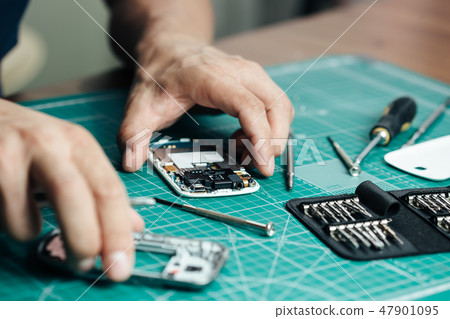 Electronics repair service. Technician disassembling smartphone for inspecting 47901095