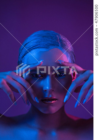 Beautiful stylish model holds hands near the face in a neon shade. 47906500