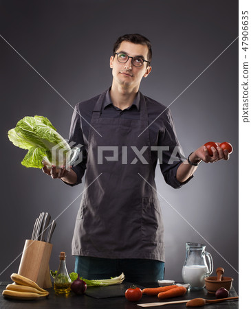Man preparing delicious salad with tomatoes and cabbage on a gray background. 47906635