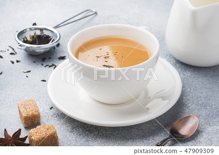 Cup of tea with milk, brown anise sugar  47909309