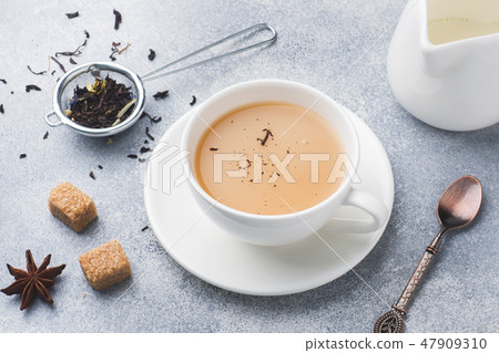 Cup of tea with milk, brown anise sugar  47909310