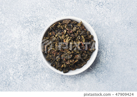 Tea leaves for brewing in bowl on a gray backgroun Tea leaves for brewing in bowl on a gray backgroun 47909424