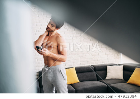 Man Working Out At Home With App On Mobile Phone 47912384