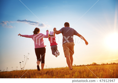 girl with mother and father holding hands on the nature 47912947