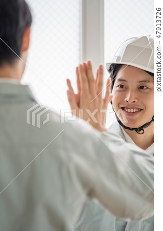 通過完成施工現場培訓和手牽著手微笑兩個商界人士的高觸摸工作的年輕人 47913726