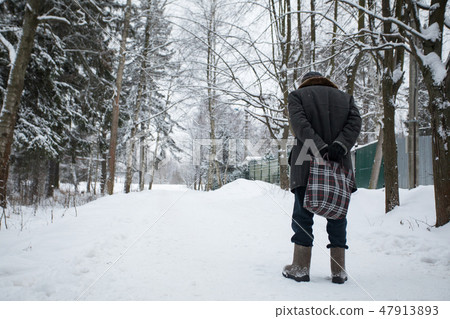 The old man goes with a bag in the winter on the road The old man goes with a bag in the winter on the road 47913893