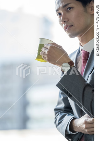 One male businessman who drinks coffee at the window at rest and heals work fatigue One male businessman who drinks coffee at the window at rest and heals work fatigue 47914039