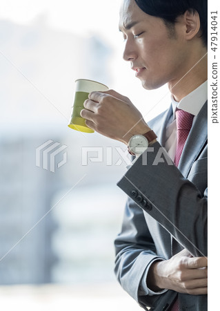 A male businessman who drinks coffee on the window at work break time and heals work fatigue A male businessman who drinks coffee on the window at work break time and heals work fatigue 47914041