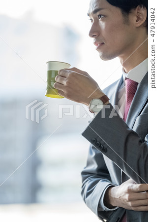 One male businessman who drinks coffee at the window while he is working and heals work fatigue 47914042