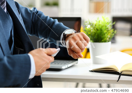 Man in suit and tie check out time at silver wristwatch 47914690