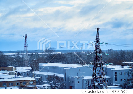 Power transmission line tower against blue sky and clouds with snow-covered high-voltage insulators Power transmission line tower against blue sky and clouds with snow-covered high-voltage insulators 47915003