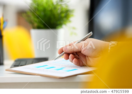 Male arm hold silver pen examining stats graphic Male arm hold silver pen examining stats graphic 47915599