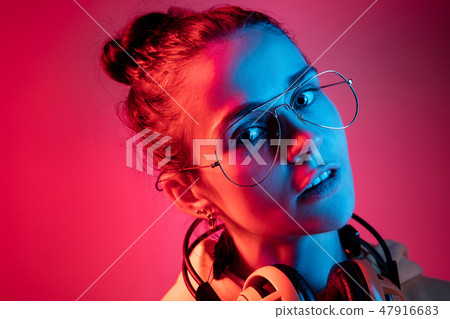 Fashion pretty woman with headphones listening to music over neon background 47916683