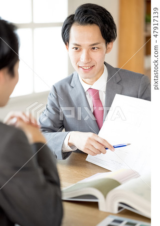 A young first-class architect of a design office who presents contract drawing and explains important items to customers Male businessman 47917139