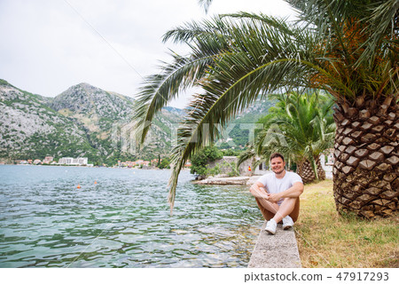 man sitting at seaside with beautiful view. mountains on background man sitting at seaside with beautiful view. mountains on background 47917293