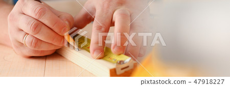Arms of worker measuring wooden bar Arms of worker measuring wooden bar 47918227