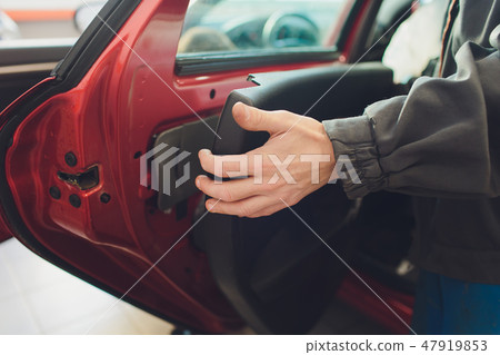 Mechanic installing car central door lock motor. 47919853