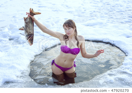 Girl with fish standing in the ice-hole. 47920270