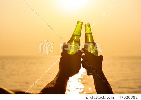 Couple hands clanging beer bottle at the beach Couple hands clanging beer bottle at the beach 47920385