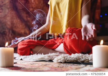 Close-up of woman's hand in yoga lotus pose meditating in a crafting room with candles Close-up of woman's hand in yoga lotus pose meditating in a crafting room with candles 47920854